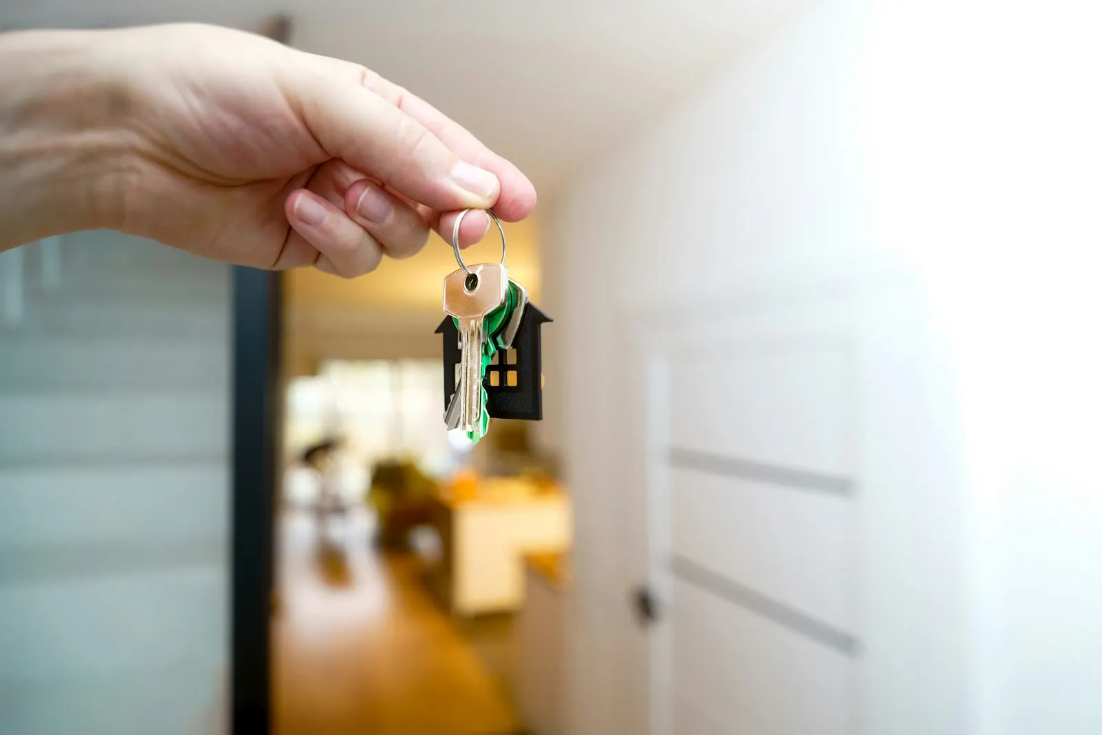 Main tenant un trousseau de clés avec porte-clés en forme de maison